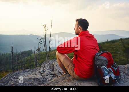 Man sitting on rock en profitant de la vue au cours de promenades à pied Banque D'Images
