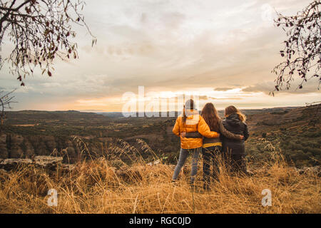 L'Espagne, Alquezar, trois amis s'embrassant sur une colline avec vue sur le paysage Banque D'Images