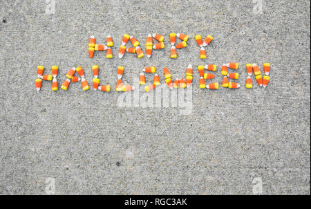 L'expression Happy Halloween énoncées avec candy corn sur un trottoir. L'expression est centerd dans la partie supérieure de la photo. Banque D'Images