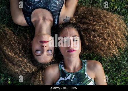 Portrait de deux sœurs jumelles rouged allongé sur une prairie, vue du dessus Banque D'Images