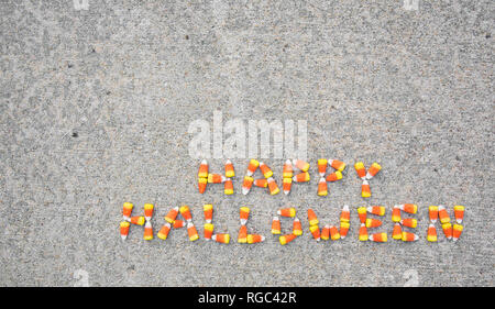 L'expression Happy Halloween énoncées avec candy corn sur un trottoir. L'étape est situé dans la partie inférieure droite de la photo. Banque D'Images