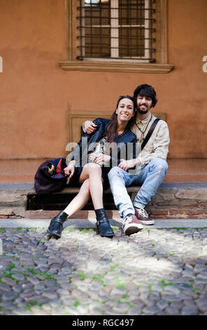 Portrait of happy young couple sitting on steps outdoors Banque D'Images