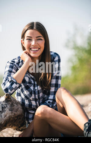 Portrait of happy young woman sitting outdoors Banque D'Images