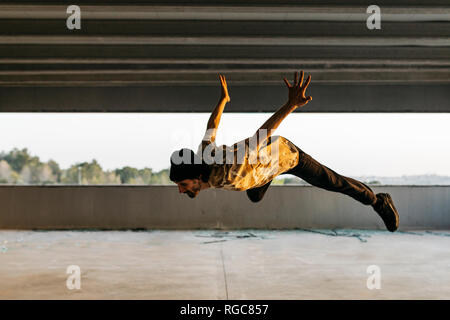 L'homme faisant le breakdance en milieu urbain en béton, jumping mid air Banque D'Images