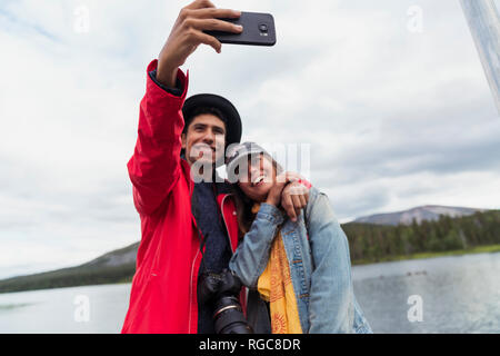 La Finlande, Laponie, couple heureux de prendre un à un lac à selfies Banque D'Images