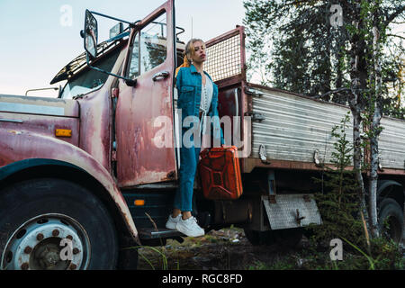 Young woman posing at a broken vintage camion, essence peut maintenant Banque D'Images