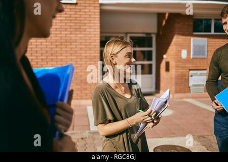 Smiling students standing en plein air avec des documents Banque D'Images