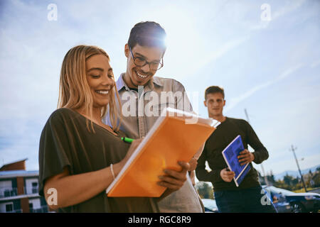 Happy students standing outdoors partage de documents Banque D'Images