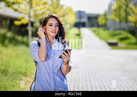 Portrait d'étudiant en utilisant écouteurs smartphone et sur le campus Banque D'Images