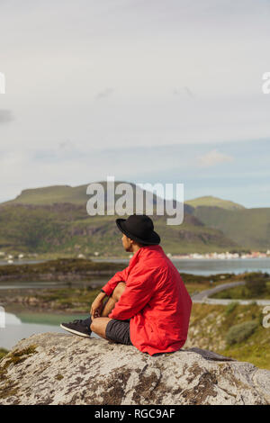 Jeune homme assis sur un rocher dans l'île de Vesteralen, Laponie, Norvège Banque D'Images