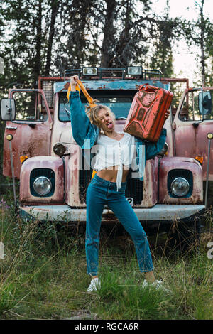 Young woman posing at a broken vintage camion, essence peut maintenant Banque D'Images