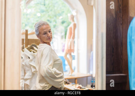 Smiling senior woman trying on pull dans une boutique Banque D'Images