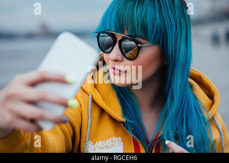 Portrait de jeune femme avec les cheveux teints en bleu avec le smartphone selfies Banque D'Images