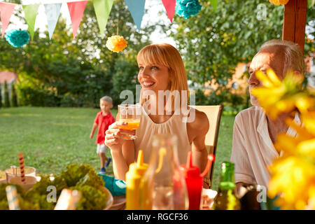 Smiling woman drinking orange juice on a garden party Banque D'Images