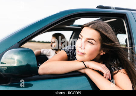 Smiling young woman leaning out of car window Banque D'Images