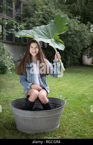 Portrait of smiling girl sitting sous les grandes en remous dans dans le jardin Banque D'Images