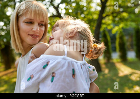 Heureuse mère portant sa fille dans le jardin Banque D'Images