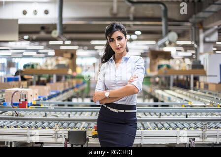 Portrait of smiling woman at conveyor belt in factory Banque D'Images