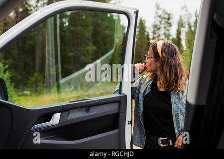 La Finlande, Laponie, jeune femme sur une voiture in rural landscape Banque D'Images