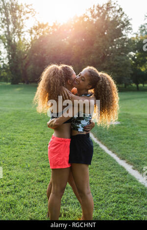 Twin Sisters hugging mutuellement dans un parc Banque D'Images