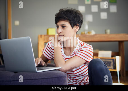 Smiling woman using laptop at home Banque D'Images