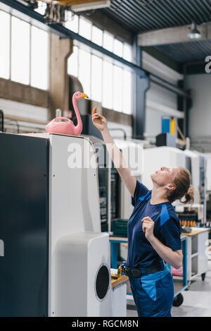Jeune femme travaillant à titre de travailleur qualifié dans une entreprise de haute technologie, en jouant avec un flamant rose Banque D'Images