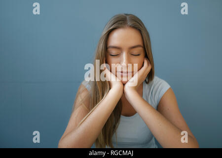 Portrait de jeune femme avec les yeux fermés et la tête dans les mains se détendre Banque D'Images