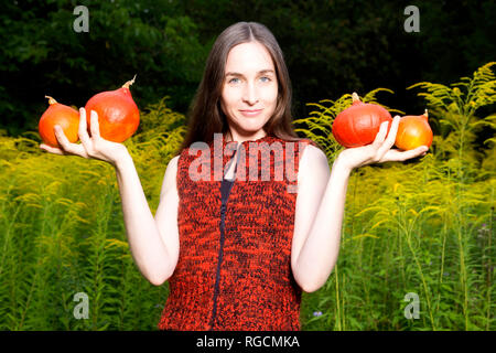 Portrait of smiling woman in the garden holding quatre citrouilles Hokkaido bio Banque D'Images