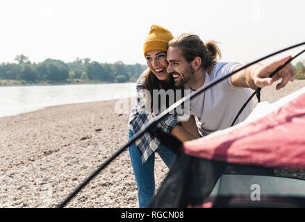 Happy young couple mise en place d'une tente au bord du fleuve Banque D'Images