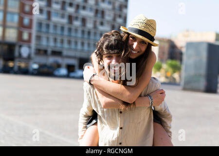 Portrait of happy young man giving his girlfriend a piggyback ride Banque D'Images