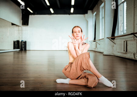 Red-haired teenager en pantalon orange faisant tordre des bras Banque D'Images