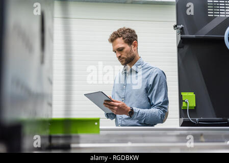Businessman in high tech entreprise qui contrôle les machines de fabrication, using digital tablet Banque D'Images