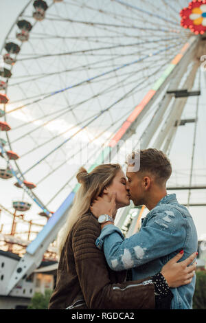 Happy young couple embracing et s'embrasser lors d'une fête foraine Banque D'Images