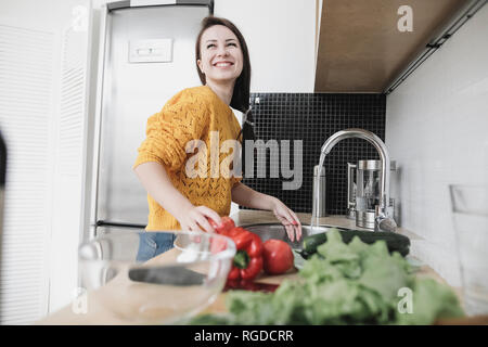 Portrait of happy young woman preparing salad in modern kitchen Banque D'Images