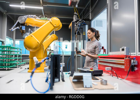 Businesswoman contrôler un robot industriel dans une entreprise de haute technologie Banque D'Images