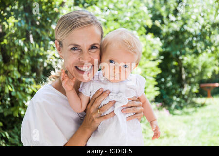 Portrait of happy mother holding her baby girl outdoors Banque D'Images