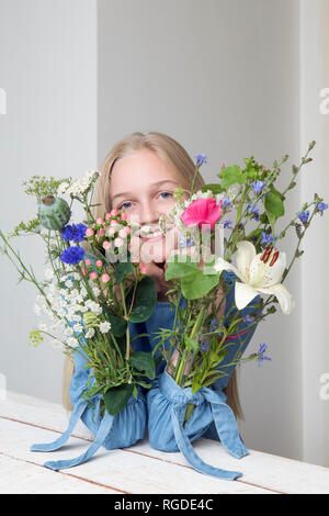 Portrait of smiling blonde avec des bouquets de fleurs dans les manches de sa robe Banque D'Images