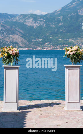 Arrangements de fleurs sur des béquilles pour une cérémonie de mariage sur la jetée contre la mer, Close up Banque D'Images