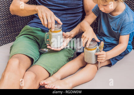 Père et fils manger le dessert avec chia seeds et de mangues à la piscine le matin. la saine alimentation, l'alimentation, les régimes végétariens et personnes concept Banque D'Images