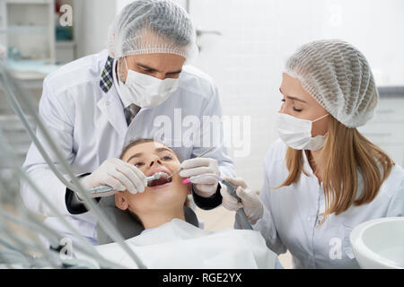 Dentiste et sous-utilisation de client. Femme couchée avec bouche ouverte sur dentiste président. Stomatologists la prévention de la carie dentaire à l'aide de la restauration d'instruments et d'outils. Banque D'Images