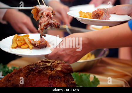 Serveur sert de viande rôtie et pommes de terre au four à la fête ou réception de mariage Banque D'Images