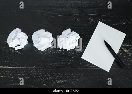 Concept de rédiger des documents et de la difficulté à écrire un texte, un jeu de boules de papier et fronça le bloc-notes vide sur fond sombre moody Banque D'Images