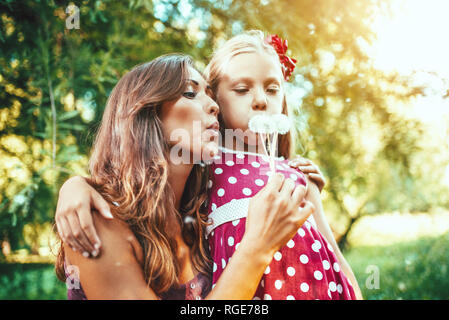 Happy cute little girl blowing dandelion avec mère dans le parc. Banque D'Images