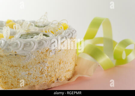 Gâteau sur un fond blanc et rose avec un ruban vert tourné du côté Banque D'Images