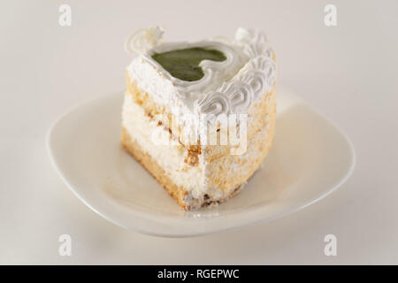 Morceau de gâteau sur une assiette blanche tourné du côté Banque D'Images