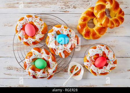 Des petit pain de Pâques oeufs teints avec des anneaux sur une vieille table en bois blanc n, vue de dessus, flatlay Banque D'Images