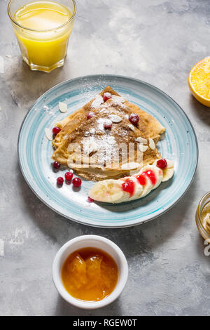 Crêpes traditionnelles de banane et fruits rouges sur fond de béton. Banque D'Images