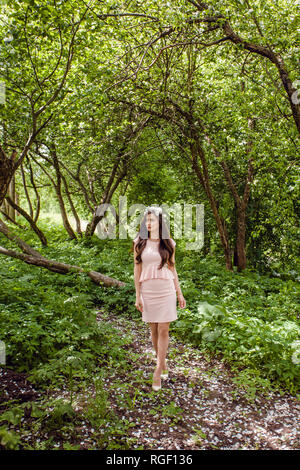 Jolie jeune femme en robe rose à fleurs jardin permanent à l'extérieur. Belle fille portrait en extérieur Banque D'Images