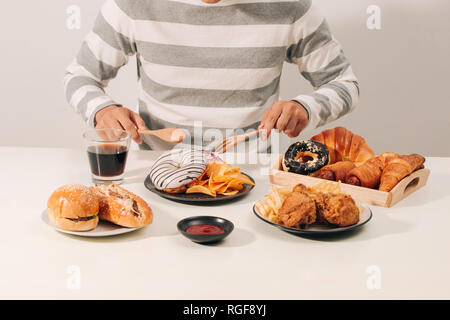 Homme avec plusieurs type de restauration rapide. Concept d'aliments malsains Banque D'Images