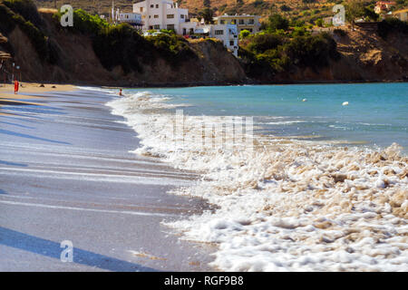 Surfez et vague de mousse des vagues sur une plage de sable. Sunny sandy Livadi Beach dans la baie de la mer de Bali village resort. Les vagues de la mer de sable de la plage déserte. Bali, Rethymno, Crète, Grèce Banque D'Images